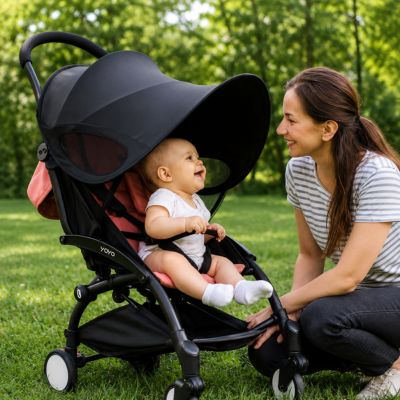bébé souriant à maman accroupie en face de lui est assis dans poussette avec pare soleil poussette