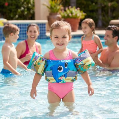 fillette avec brassard flottant dans piscine avec sa famille