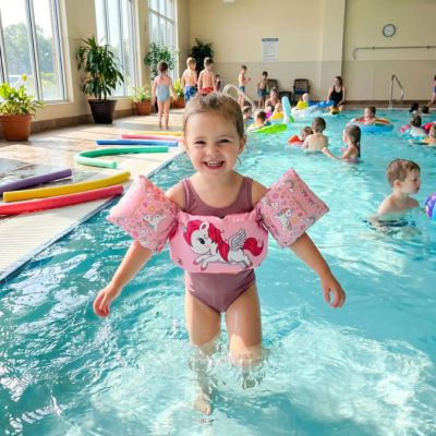 fillette avec brassard flottant dans piscine intérieur avec d'autres enfants