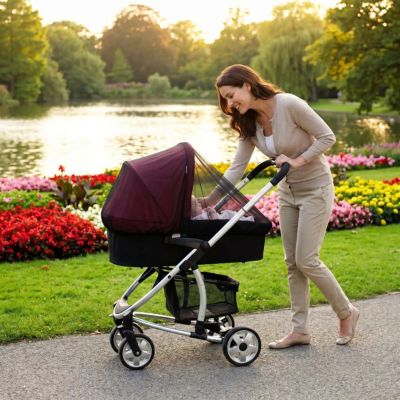 maman promenant bébé dans moustiquaire poussette dans parc au bord d'un lac 