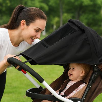 bébé souriant dans poussette avec par soleil poussette et maman le regardant souriante aussi