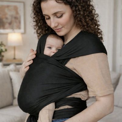 maman en train de calmer bébé en le portant dans porte bebe echarpe