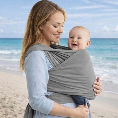maman marchent sur la plage et portant bébé dans porte bebe echarpe