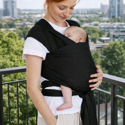 maman sur balcon portant bébé dans porte bebe echarpe