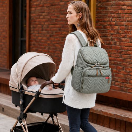 sac a dos a langer porté par jeune maman marchant en ville avec bébé dans poussette