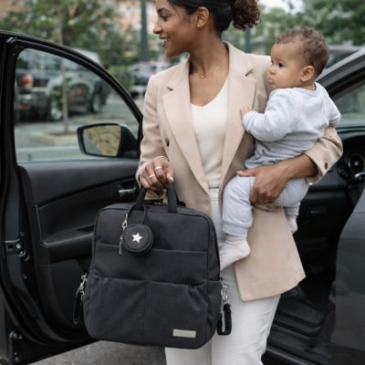 maman très élégante pourtant bébé dans le bras gauche et sac à langer sac à dos dans l'autre