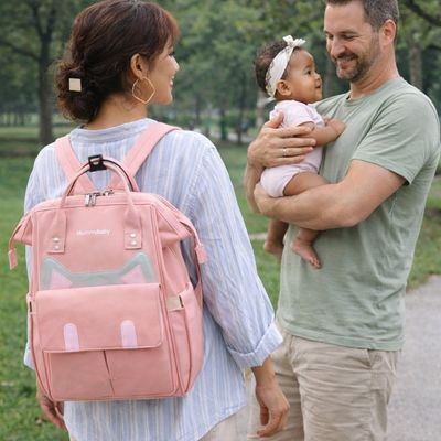 Parents se promenatn au parc avec bébé maman portant sac a dos a langer 