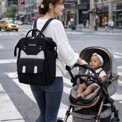 maman portant sac a dos a langer traverse rue avec bébé dans poussette