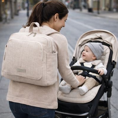 sac a dos a langer porté par maman au dos en poussant bébé dans poussette sur trottoir