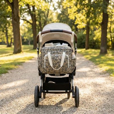 sac a langer bebe accroché à une poussette dans un parc verdoyant