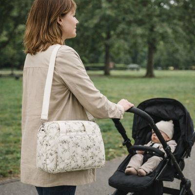 sac a langer bebe porté par bandoulière à l'épaule d'une maman qui promène bébé dans poussette au parc